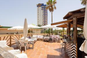 a patio with white chairs and tables and umbrellas at Apartment on the beach Paraiso Playa, Sea Views in Playa Paraiso