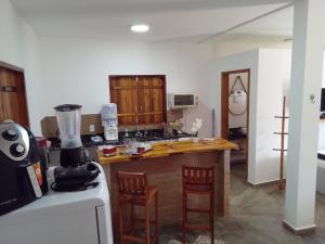 a kitchen with a counter with two chairs and a counter top at Chales Paraíso STL in São Thomé das Letras