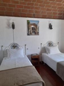 a bedroom with two beds and a brick wall at Monte do Ribeiro Baço - Monsaraz in Monsaraz