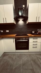 una cocina con armarios blancos y horno negro en South Yorkshire House, en Mexborough 1 foto más