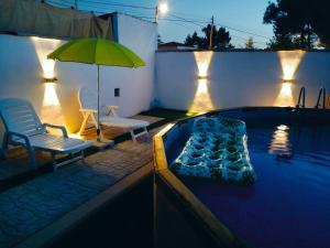 a swimming pool with a green umbrella and two chairs and a table at Casa Valle del Hontanar in Cardenete