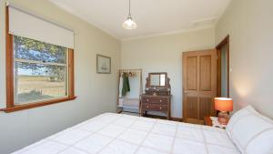 une chambre avec un lit, une commode et un miroir dans l'établissement Cane Cutters Cottage, à Woombah 16 autres photos