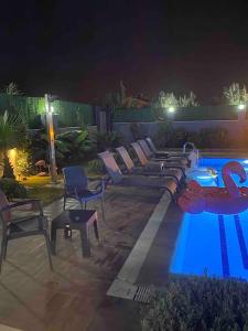 a pool with couches and chairs next to a swimming pool at night at Melisa Luxury Villa in Dosemealti