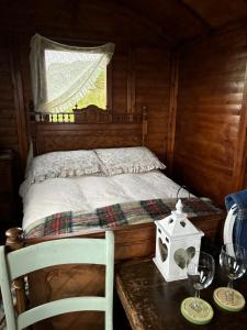 a bedroom with a bed and a table with wine glasses at Eco Crofter's Wagon by the Sea - Off Grid Experience - No electricity - As seen soon on Netflix in Oldshoremore