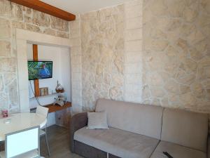 een woonkamer met een bank en een stenen muur bij Apartment Nada in Rogoznica