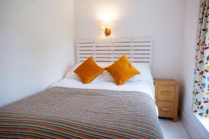 a bedroom with a bed with two orange pillows at 26 Rosemary Lane in Beaumaris