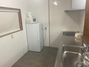 a small kitchen with a white refrigerator and a microwave at 宮の宿 in Fujinomiya