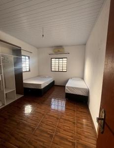 ein Zimmer mit zwei Betten und Holzboden in der Unterkunft Aurora dos Pireneus in Pirenópolis