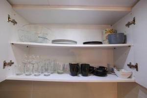 a shelf with glasses and other glass items on it at Elegant studio at the Acropolis hills in Athens +3 photos