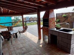 a patio with a kitchen with a stove and a table at Casa Lagoa e Praia Rosa in Praia do Rosa +19 photos