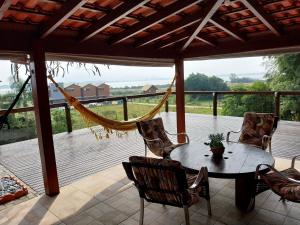 a porch with a hammock and a table and chairs at Casa Lagoa e Praia Rosa in Praia do Rosa