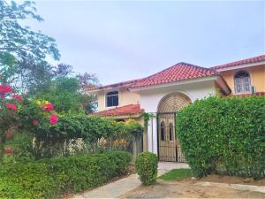 a house with a gate and some bushes and flowers at Linkzup Playa Laguna Villa in Sosúa