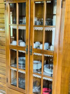 a wooden cabinet with plates and dishes in it at Casa Albatroz do Rosa - Albatroz Hospedaria in Imbituba