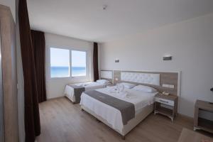 a hotel room with two beds and a large window at Seymen Otel in Kizkalesi