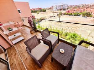 a balcony with chairs and a table and a view of a city at Appartement Luxueux avec Piscine 10 minutes du centre ville in Marrakech