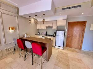 a kitchen with a bar with red chairs in it at Appartement Luxueux avec Piscine 10 minutes du centre ville in Marrakech