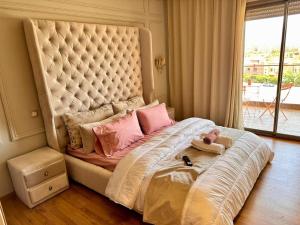 a large bed with pink pillows and a large headboard at Appartement Luxueux avec Piscine 10 minutes du centre ville in Marrakech +21 photos