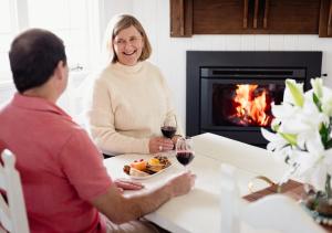 a man and a woman sitting at a table with a glass of wine at Pretty Pink Queenslander - Spectacular Views, Space and Serenity in Tenterfield