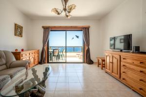 a living room with a couch and a tv at Atlantic View Tenerife South in Arona