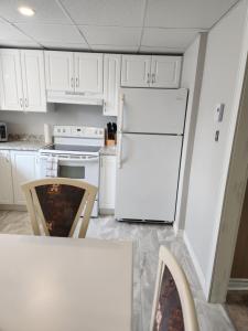 a kitchen with white cabinets and a white refrigerator at Appartement de la rive 2 in Shippagan