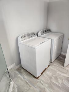 a laundry room with two washing machines and a tile floor at Appartement de la rive 2 in Shippagan