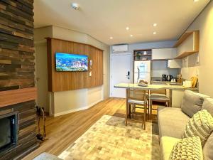 een woonkamer met een bank en een keuken met een open haard bij Luxuoso Studio no Serra Class (307) in Canela