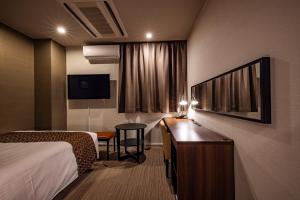 a hotel room with a bed and a desk at Hotel Quest Shimizu in Shizuoka