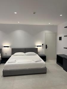 a white bedroom with a large bed and a mirror at Adele Hotel Ksamil in Ksamil