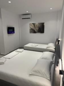 a room with two beds and a tv on the wall at Adele Hotel Ksamil in Ksamil