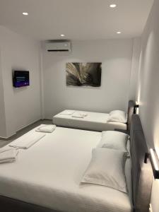 two beds in a small room with white walls at Adele Hotel Ksamil in Ksamil