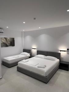 two beds in a bedroom with white walls and lights at Adele Hotel Ksamil in Ksamil