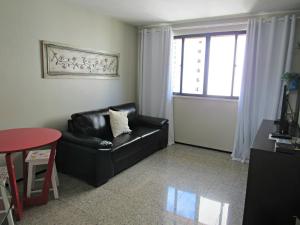 a living room with a black leather couch and a window at Residencial em Meireles in Fortaleza