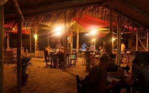 a group of people sitting at tables in a restaurant at night at Zaigon Kite Surf in Máncora