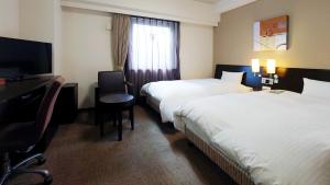 a hotel room with two beds and a desk and a television at Hotel Route-Inn Aomori Chuo Inter in Aomori +27 photos