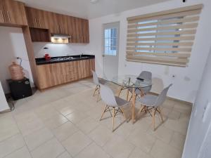 cocina con mesa de cristal y sillas blancas en Hacienda San José, en Querétaro