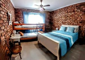 a bedroom with a bed and a brick wall at Boknesstrand Self-catering Accommodation Holiday Home - a Mermaids Cottage minutes to the beach, lagoon, shops & more! in Boknes