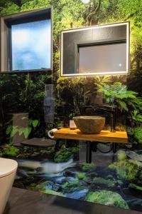a bathroom with a bowl on a table in front of a river at Punakaiki Treehouse Limited in Punakaiki