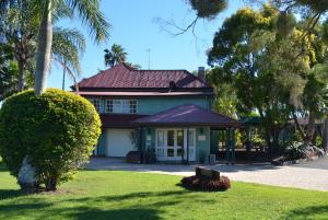 una casa con techo rojo en un patio verde en Puffers Inn en Loganholme