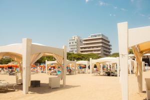 ein Strand mit Sonnenschirmen und Menschen auf dem Sand in der Unterkunft 100 m from the beach with CABANA and JACUZZI included in Lignano Sabbiadoro