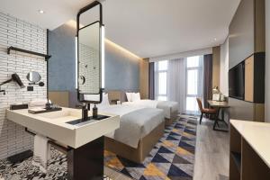 a hotel room with a bed and a sink at Wanda Moments Nanchang in Xinjian