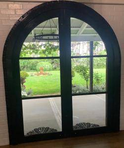 an arched window looking out into a yard at The Grange Berrima - The Ultimate Rural Retreat in Berrima