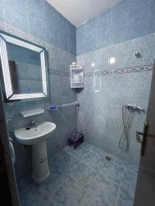 a blue tiled bathroom with a sink and a mirror at Appartement agadir in Agadir