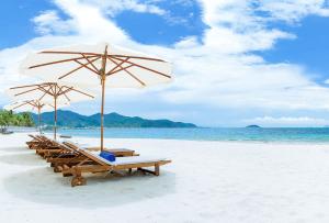 a group of lounge chairs and an umbrella on a beach at Boton Blue Hotel & Spa in Nha Trang