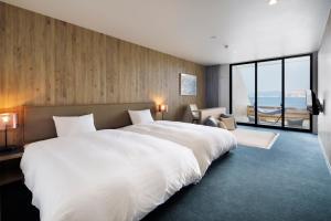 a bedroom with a large white bed and a large window at i + Land Nagasaki in Nagasaki