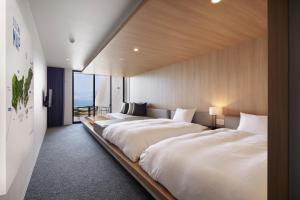 two beds in a large room with a large window at i + Land Nagasaki in Nagasaki