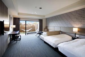a hotel room with two beds and a desk at i + Land Nagasaki in Nagasaki