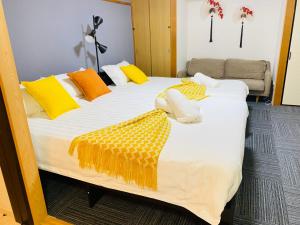 大阪大阪梅田淀川花民宿家庭房b套的一张大床,配有黄色和白色的床单和枕头