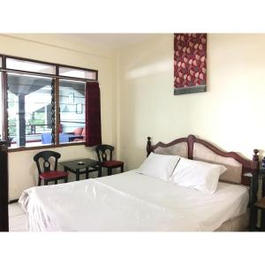 a bedroom with a bed and two chairs and a window at Hotel Lie Mas Prigen Pasuruan Mitra RedDoorz in Pasuruan