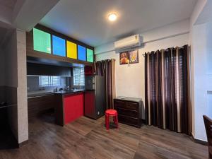 德里久尔DB Apartment Arimpur的一间带厨房的房间，配有一张桌子和一把红色凳子