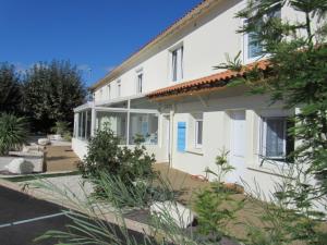 a white house with a lot of plants in front of it at Cit'Hotel Les Atlantes in Médis